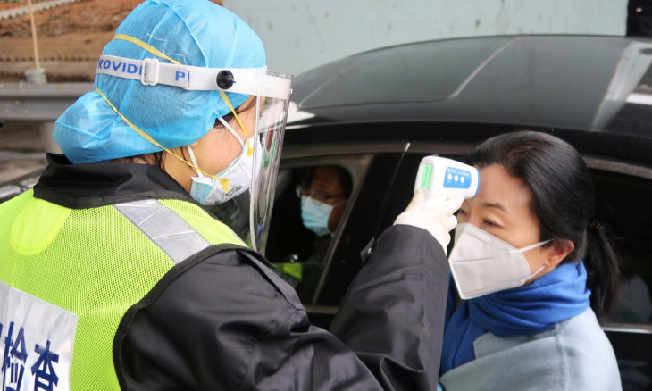 A security officer in a protective mask checks the temperature of a passenger following the outbreak of a new coronavirus, at an expressway toll station on the eve of the Chinese Lunar New Year celebrations, in Xianning