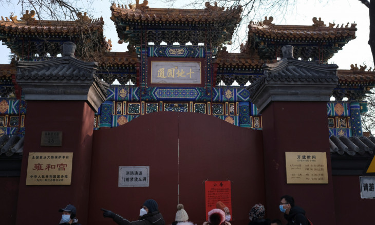 People stand in front of the closed gate of Lama Temple, with a notice saying that the temple is closed for safety concerns following the outbreak of a new coronavirus on its gate, in Beijing