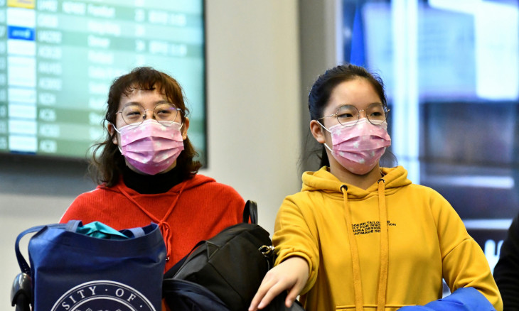 Travellers wearing masks arrive on a direct flight from China at Vancouver International Airport