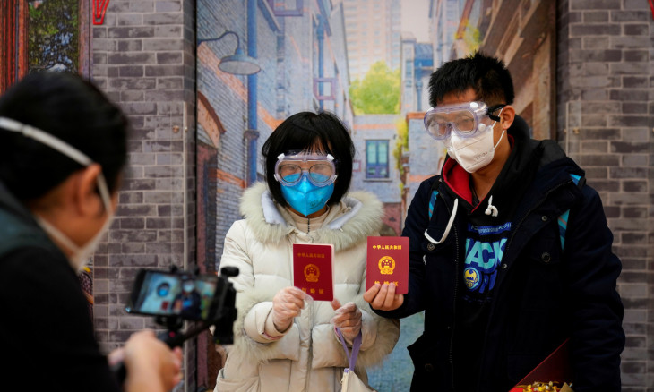 Jia, 29, and his wife Su, 28, poses with face masks and marriage certificates at a marriage registry office on Valentine's Day in Shanghai