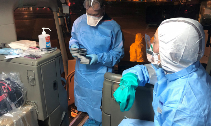 Health officials in protective suits on a shuttle bus transporting U.S. passengers who have chosen to leave the Diamond Princess cruise ship, to a chartered evacuation aircraft to fly back to the United States, at Haneda airport in Japan