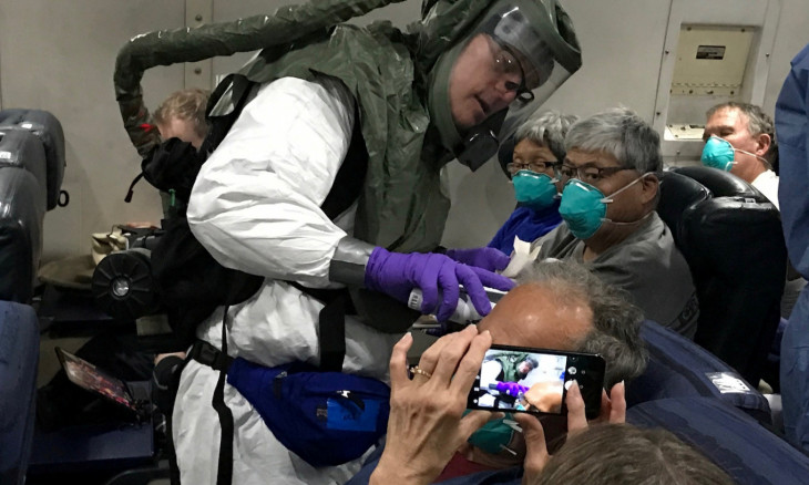 A worker in a protective suit checks the temperatures of passengers who were on board the Diamond Princess cruise ship on a chartered evacuation aircraft en route to Lackland Air Force Base in San Antonio, Texas