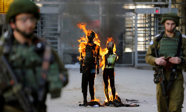Effigies depicting U.S. President Trump and Israeli PM Netanyahu are burnt by Palestinian demonstrators as Israeli soldiers stand guard during a protest in Hebron in the Israeli-occupied West Bank