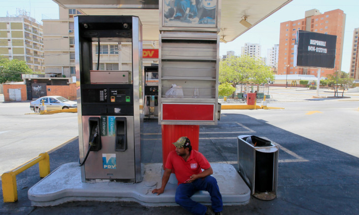 A worker sits on the floor of an empty gas station after an order to close it at the border state of Zulia in response to the spread of coronavirus disease (COVID-19) in Maracaibo