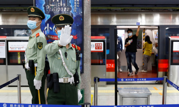A Paramilitary police officers gestures at the photographer while keeping watch at a station of Line 1 of the metro that runs past the Great Hall of the People