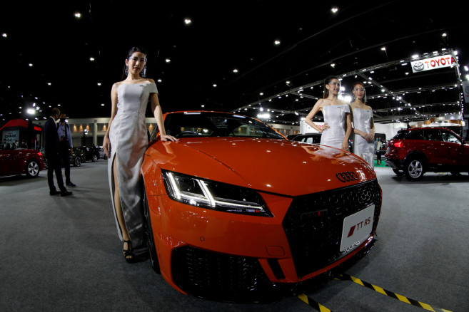 Models wearing face shields pose with an Audi TT RS Coupe