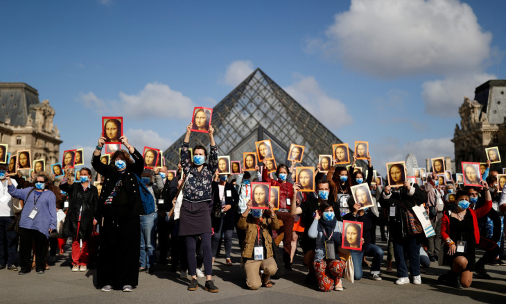 Paris tour guides hold posters depicting Mona Lisa painting 