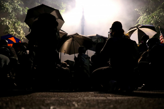 Demonstrators shelter from tear gas behind umbrellas