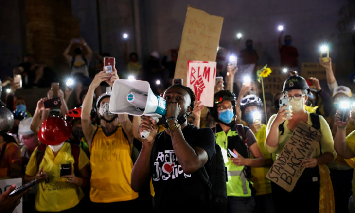Demonstrators hold lit mobile phones 