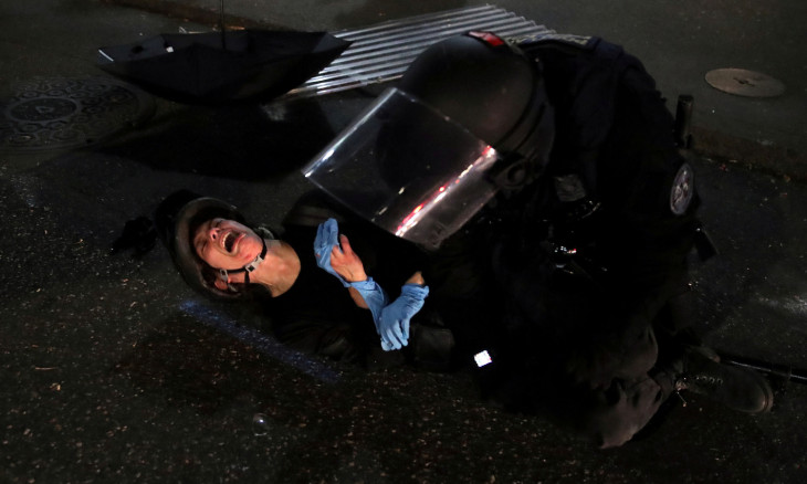 Demonstrator Dana Parks reacts as she is detained by a police officer