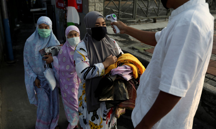 Temperature readings are taken for people attending Eid al-Adha prayers in Jakarta 