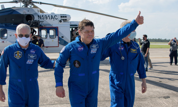 NASA astronaut Robert Behnken gives a thumbs up to onlookers as he boards a plane at Naval Air Station Pensacola