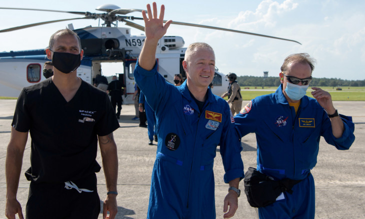 NASA astronaut Douglas Hurley waves to onlookers as he boards a plane at Naval Air Station Pensacola 