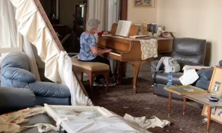 A woman plays a piano in her apartment destroyed by a blast
