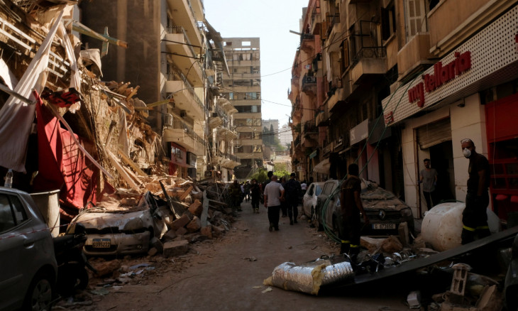 People walk past damaged buildings and vehicles following Tuesday's blast in Beirut's port area