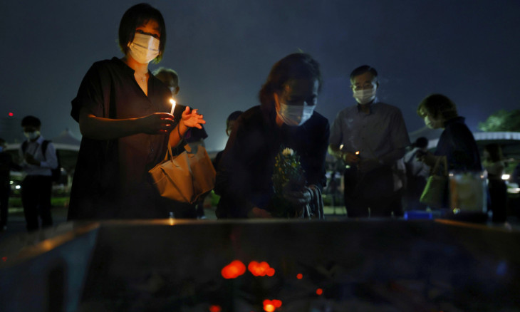 People wearing protective face masks burn incense sticks before praying for the victims of the U.S. 