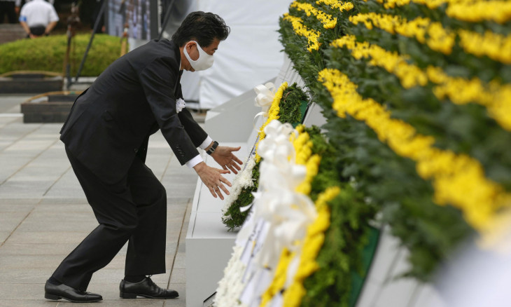 Japan's Prime Minister Shinzo Abe wearing a protective face mask, offers a wreath to the cenotaph for the victims of the 1945