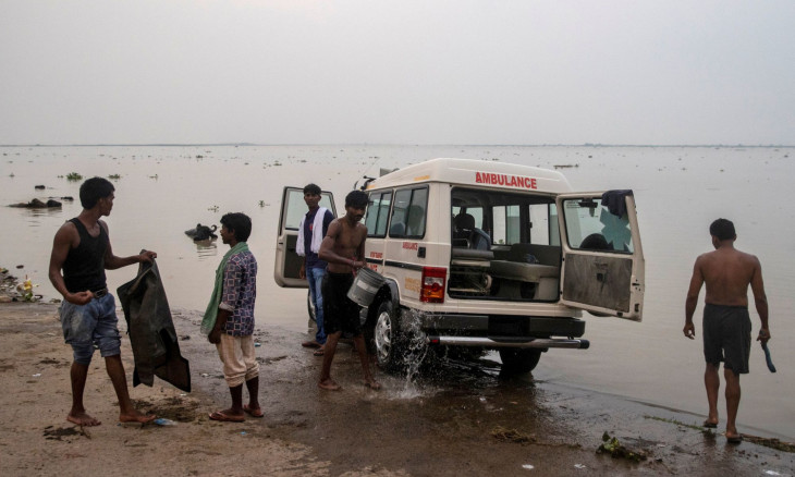 People wash an ambulance on the banks of the Ganges river 