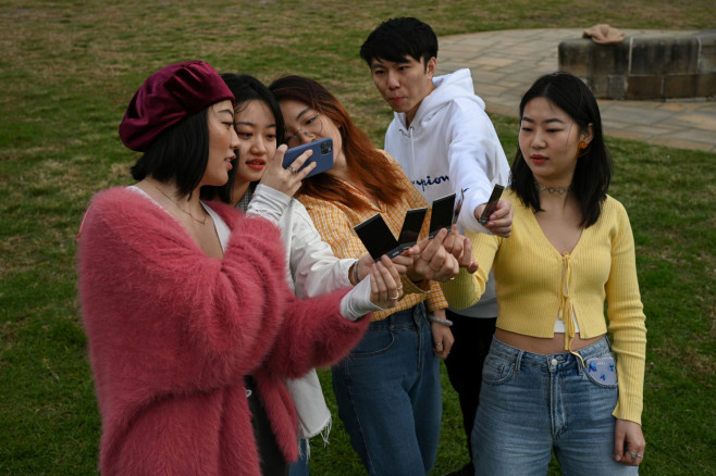 Shiyu Bao (L), an international student from China studying for a Masters in Public Relations at the University of Sydney, takes pictures with fellow students
