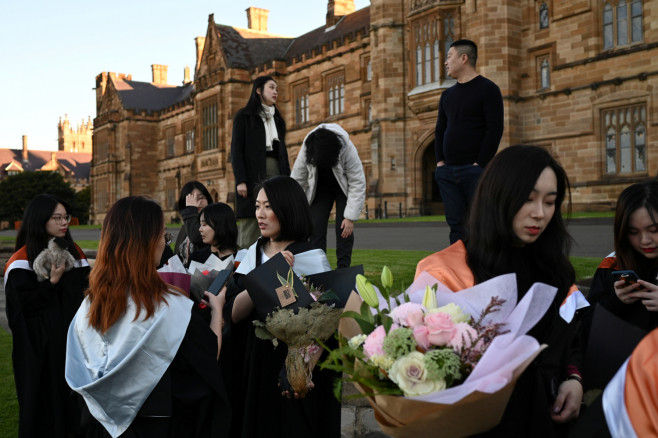 Shiyu Bao (centre) and her fellow classmates who are international students from China get ready to take pictures in their graduation gowns around campus at the University of Sydney