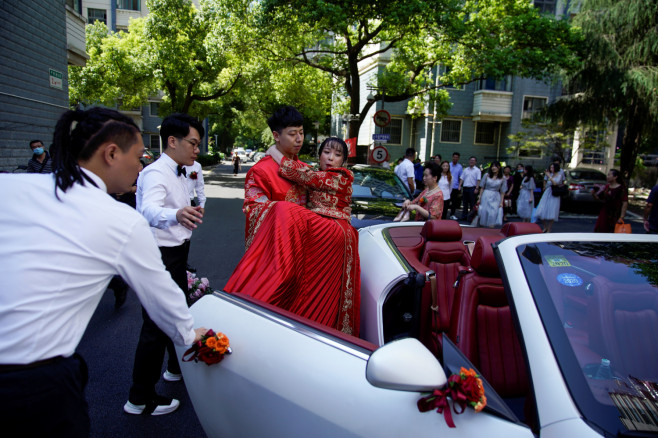 Pan Wenjun, 30, carries his bride Wei Jiawen, 29, into a car on their wedding day,