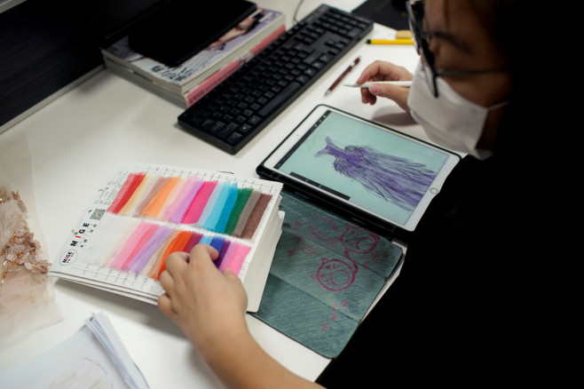 A designer looks at fabric swatches at Suzhou Jusere Wedding & Evening Dress