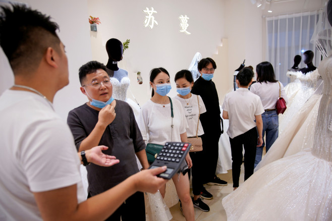 Wholesalers wear protective face masks as they visit a wedding dress store