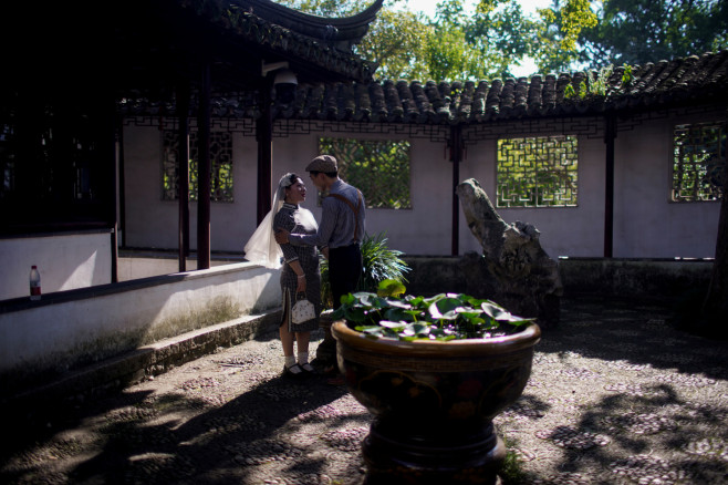 A couple pose for photographs during a wedding photo shoot at a park,