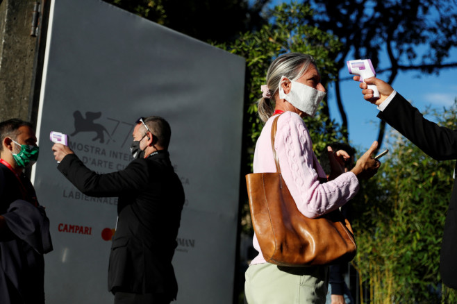 Worker check the temperature of assistants before entering to watch the first screening