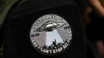 An attendee wears a patch outside a gate to Area 51 