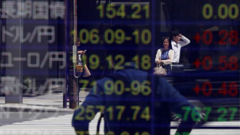Japanese yen and the U.S. dollar, the yen against the euro, the yen against the Australian dollar, Dow Jones Industrial Average and other market indices outside a brokerage in Tokyo