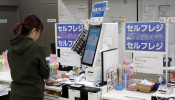 A shopper checks out at an unmanned cash register with using her mobile phone at convenience chain store Lawson in Tokyo