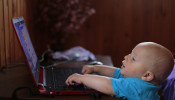 Boy wearing blue shirt using laptop.