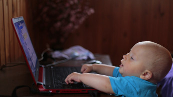 Boy wearing blue shirt using laptop.