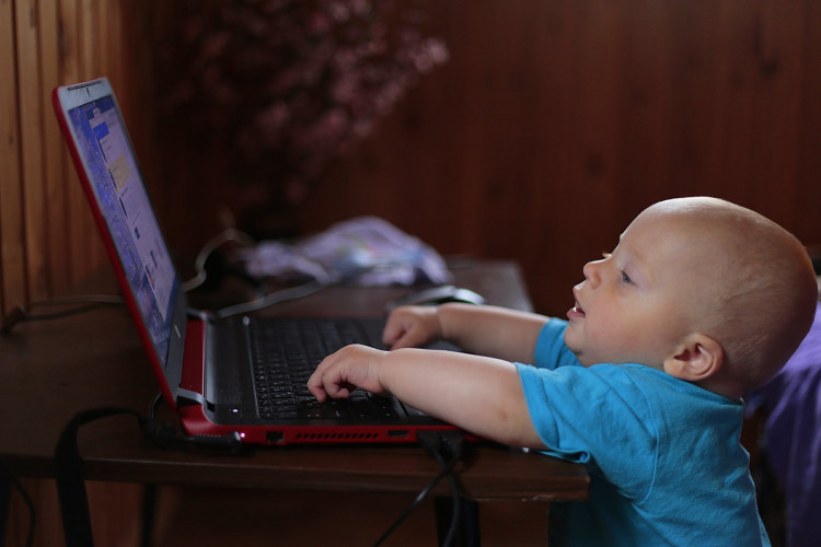 Boy wearing blue shirt using laptop.