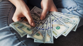 Person holding 100 US dollar banknotes.