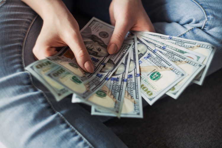 Person holding 100 US dollar banknotes.