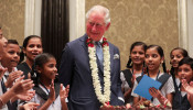 Britain's Prince Charles looks on as children from a school sing a birthday song for him in Mumbai