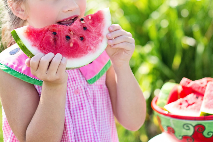 Girl eating sliced watermelon. 