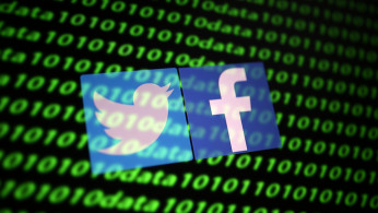 The Twitter and Facebook logo along with binary cyber codes are seen in this illustration