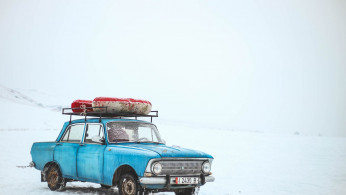 Blue sedan on snow at daytime.