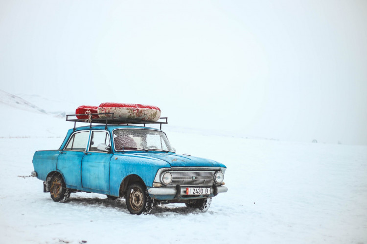 Blue sedan on snow at daytime.