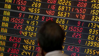 A man monitors a stock index board at a bank in Bangkok