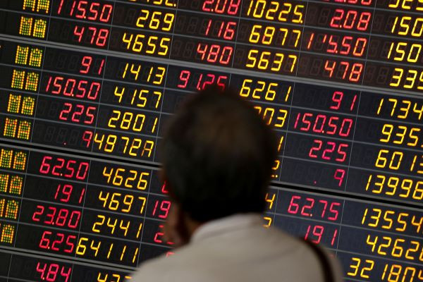 A man monitors a stock index board at a bank in Bangkok