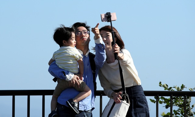 Family takes a selfie photo with a mobile phone at the Beppu Bay Service Area in Beppu