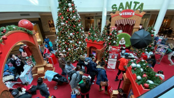Families wait in line to meet Santa Claus at Fashion Centre at Pentagon City, decorated for the holidays, in Arlington, Virginia