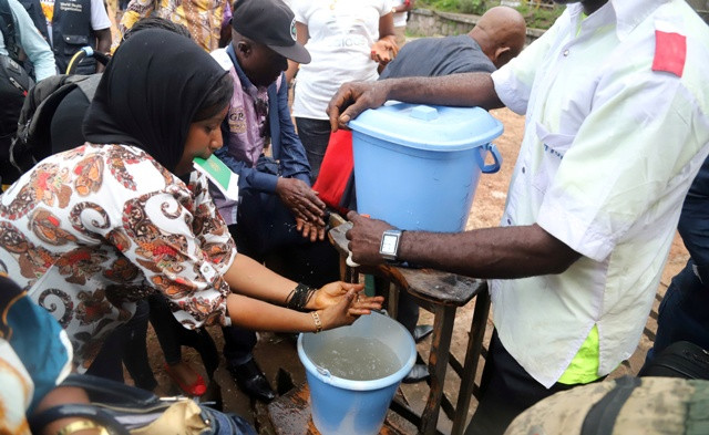 A Congolese health worker instructs residents about washing their hands 