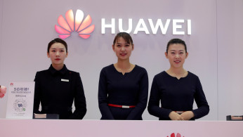 Attendants stand at a Huawei booth at the World 5G Exhibition in Beijing
