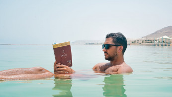Man wearing book floating while on Dead Sea.