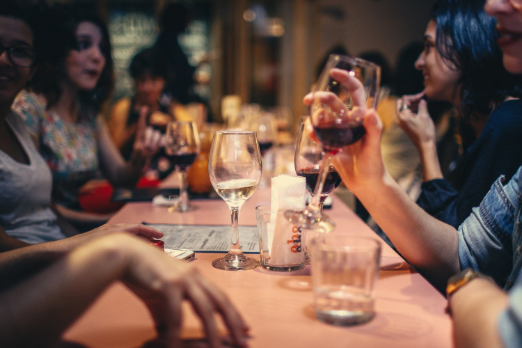 People drinking wine and talking on a dining table.